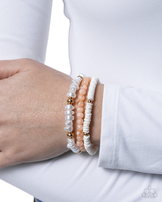 Close-up of a wrist wearing multiple beaded bracelets on a white background