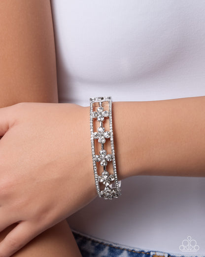 Silver bracelet with floral designs on a wrist against a white background