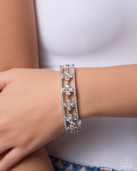 Silver bracelet with floral designs on a wrist against a white background