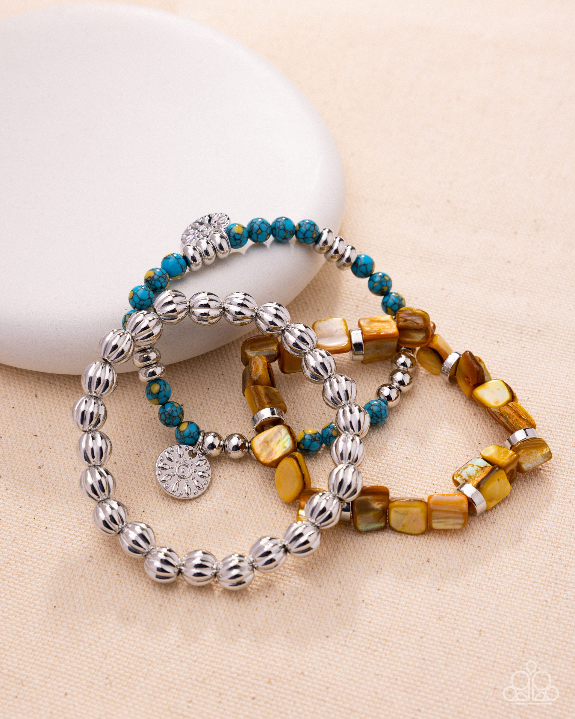 Set of beaded bracelets with silver accents on a beige surface