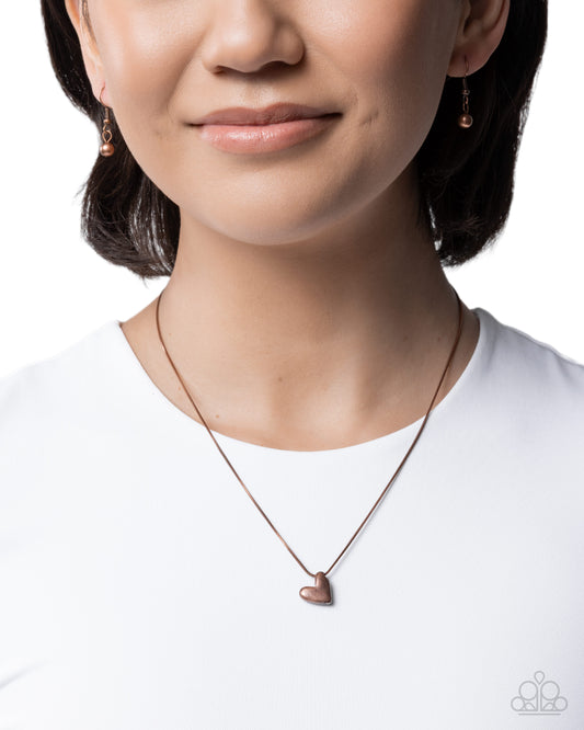 Close-up of a person wearing a heart-shaped pendant necklace on a white background