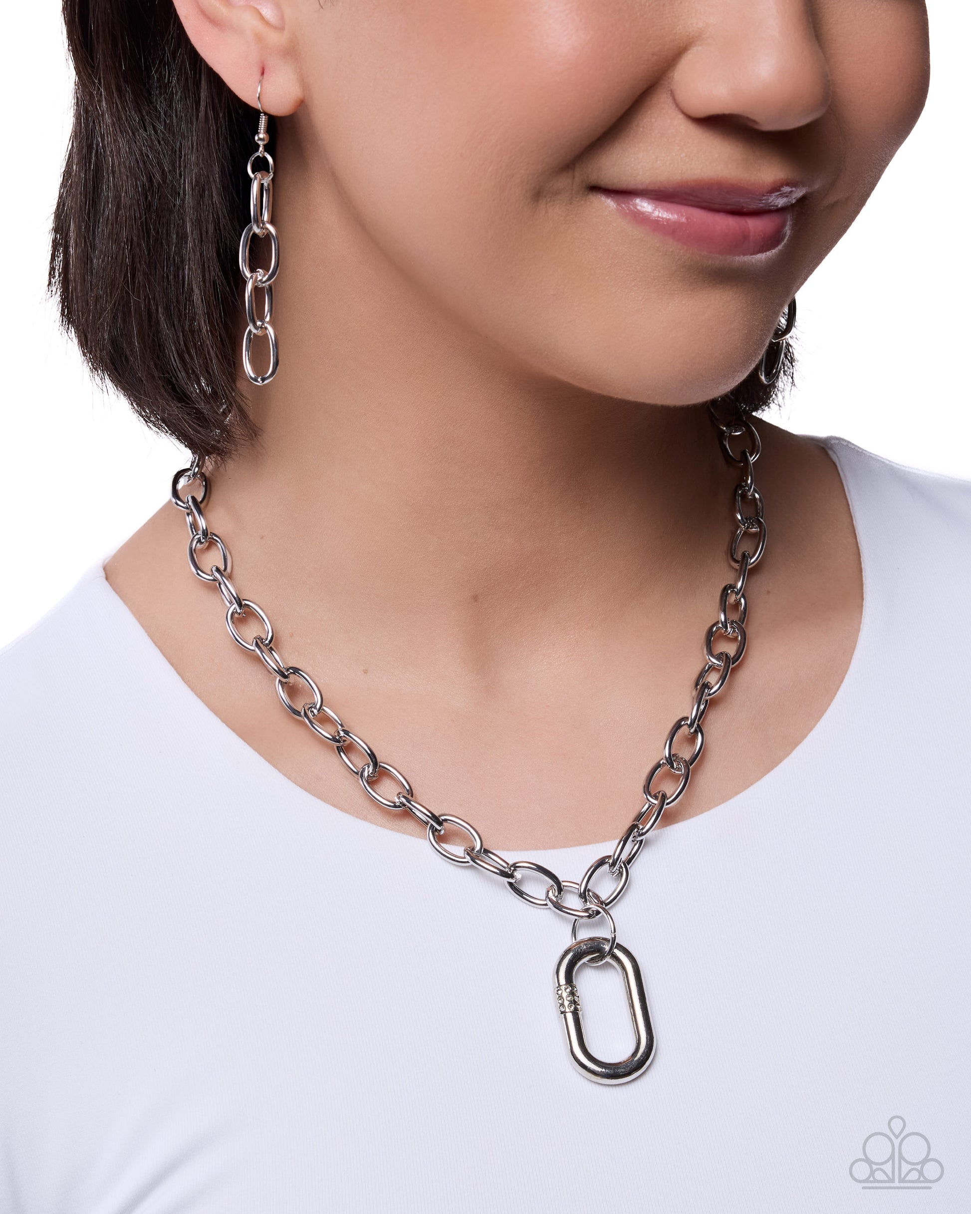 Person wearing a silver chain necklace and earrings on a white background