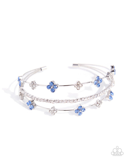 Multi-layered bracelet with blue flower charms on a white background