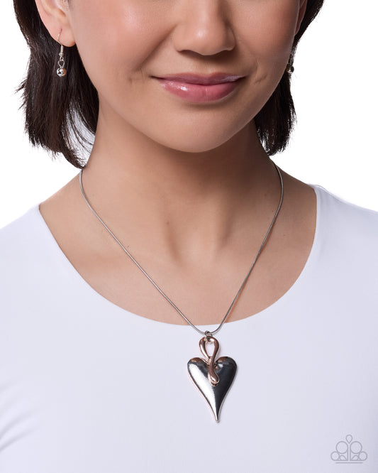 Woman wearing a silver and black heart-shaped pendant necklace on a white background