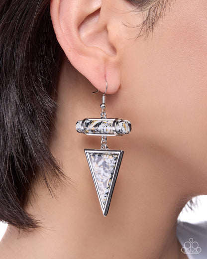 Close-up of an ear wearing a silver triangle-shaped earring with a blurred background
