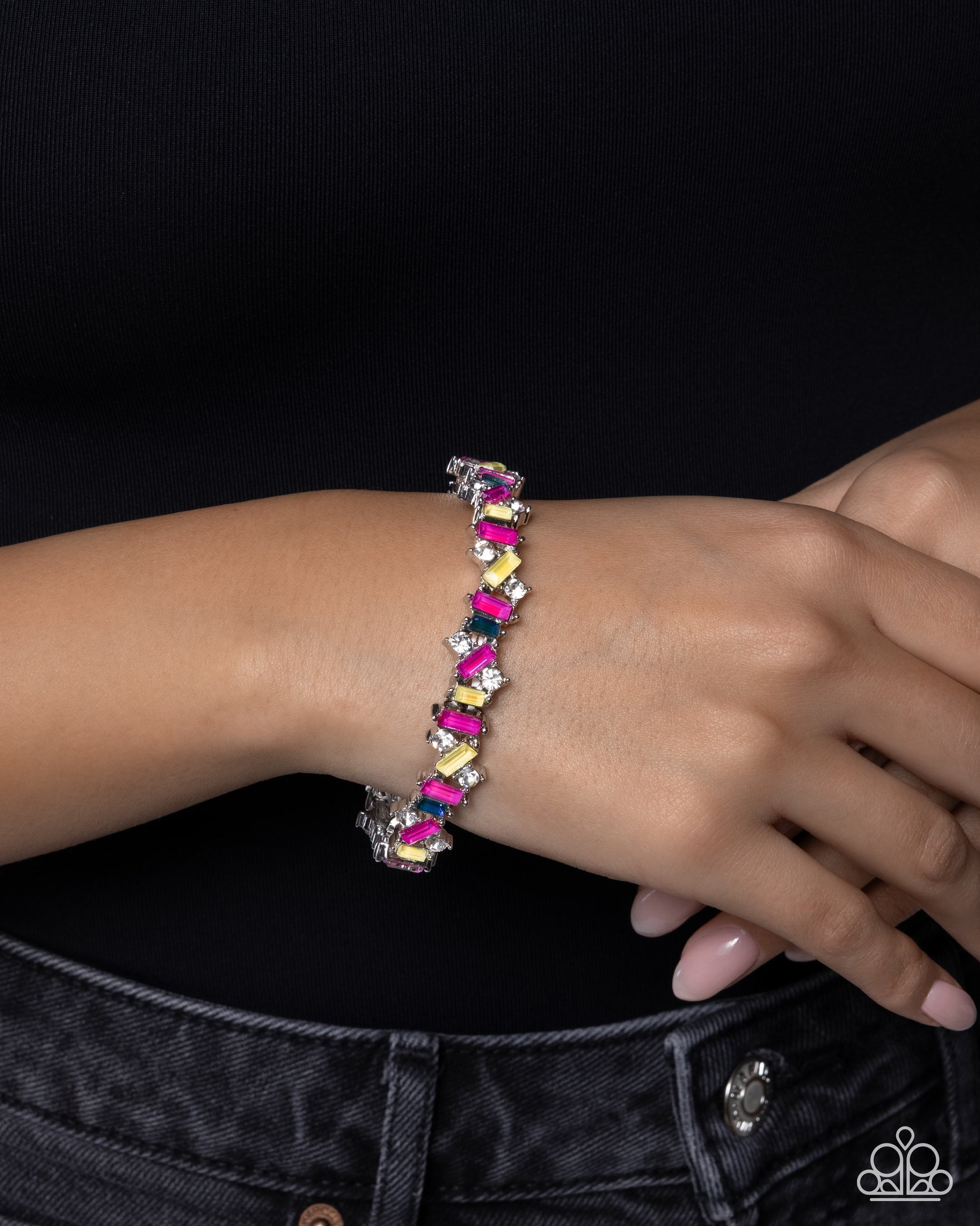 A close-up of a person's wrist wearing a colorful beaded stretch bracelet with silver-toned metal links. The bracelet features alternating bright pink, yellow, and purple beads, with some clear rhinestone accents.