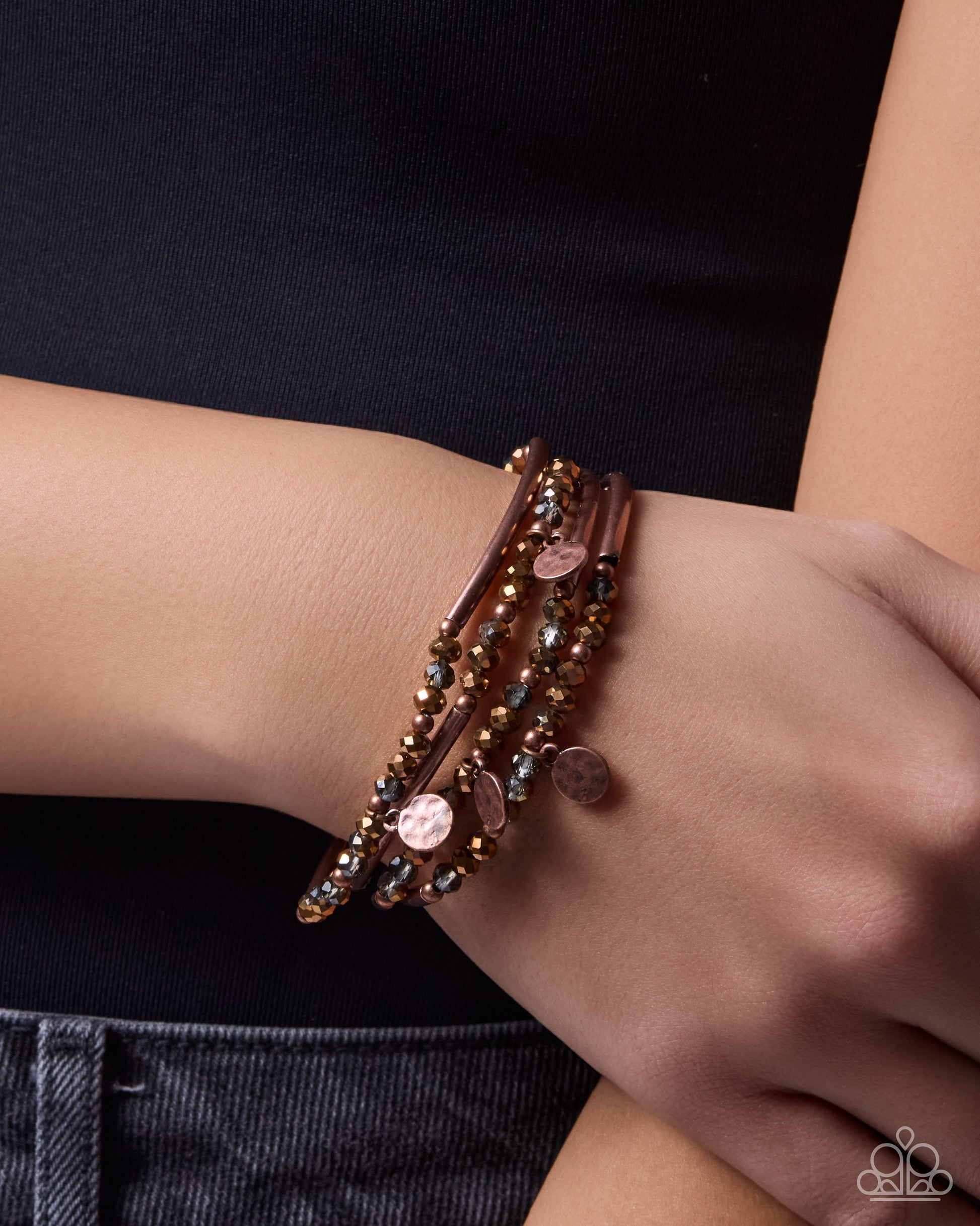 Close-up of a wrist wearing multiple bracelets with a dark background