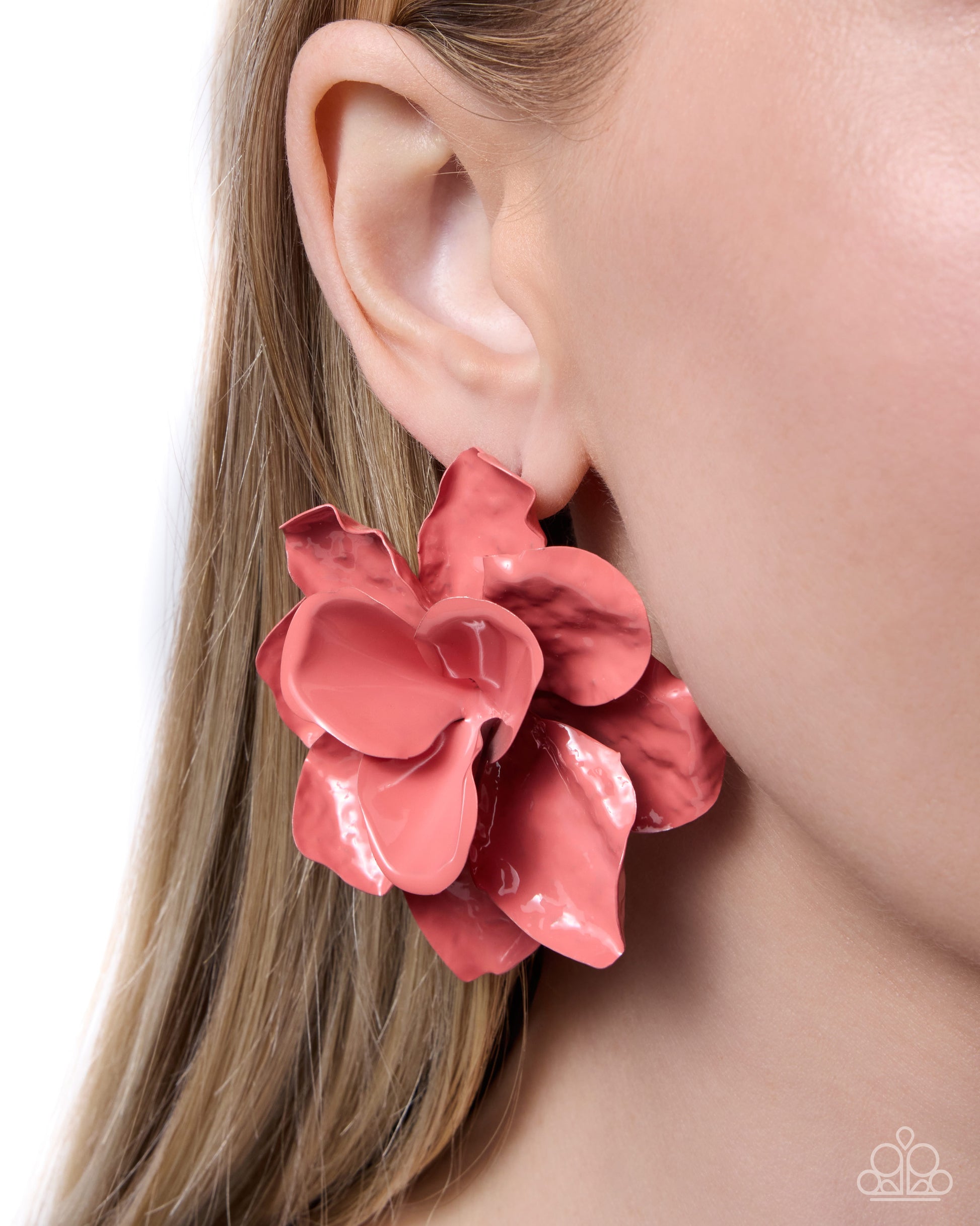 Pink flower-shaped earring worn by a person with blonde hair.