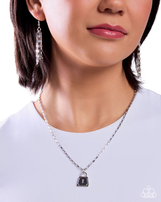 Close-up of a person wearing a silver necklace with a pendant on a white background
