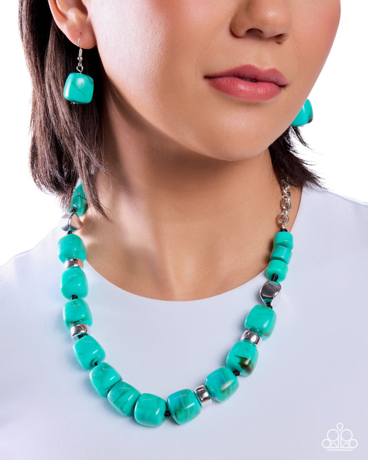 Turquoise necklace and earrings on a person wearing a white shirt