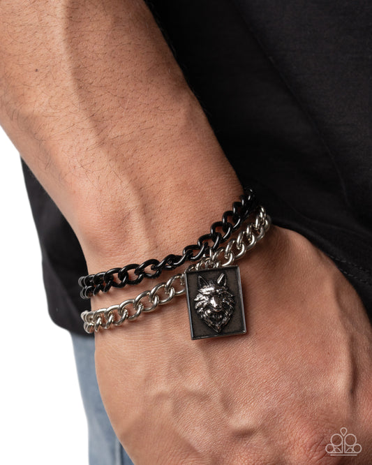 Bracelet with lion head charm on a wrist against a black background