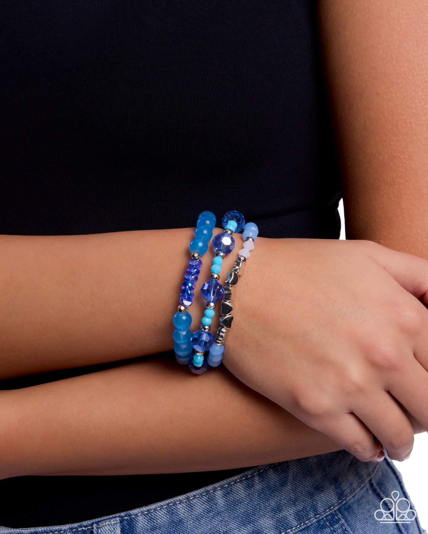 Stack of blue beaded bracelets on a wrist against a neutral background