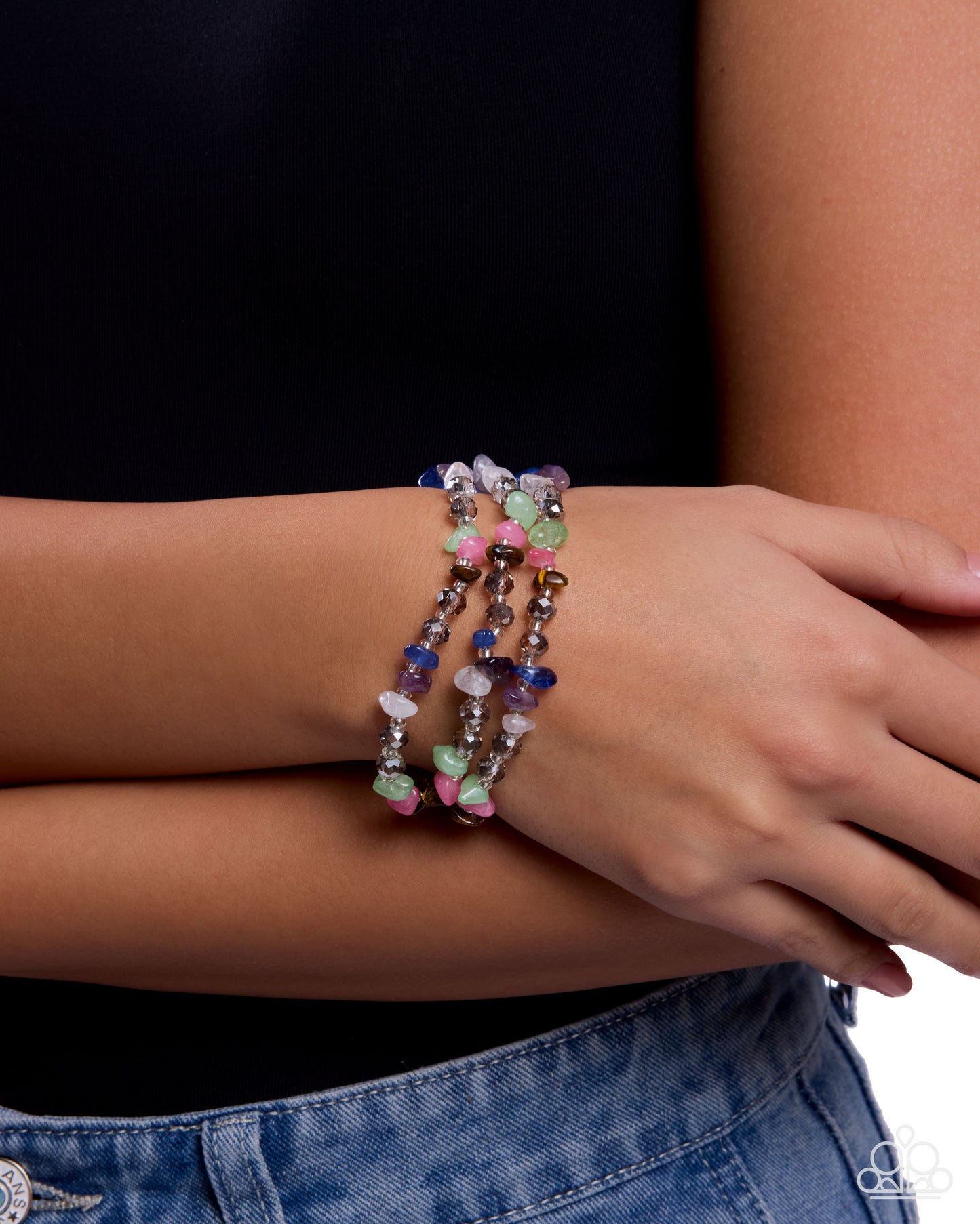 Person wearing colorful beaded bracelets on a plain background