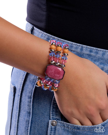 Close-up of a hand wearing a colorful beaded bracelet on a denim background