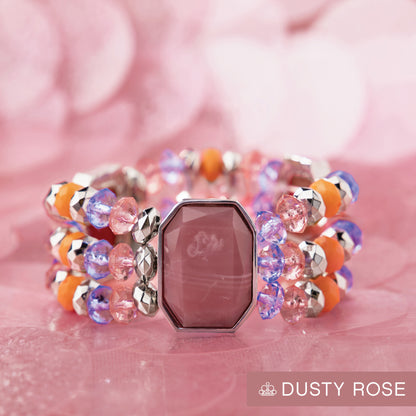 Colorful beaded bracelet with a pink gemstone on a pink background, featuring the brand 'Dusty Rose'.
