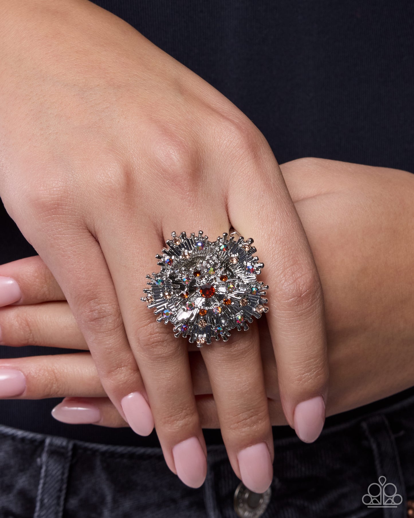 Close-up of a hand wearing a decorative ring with a black background