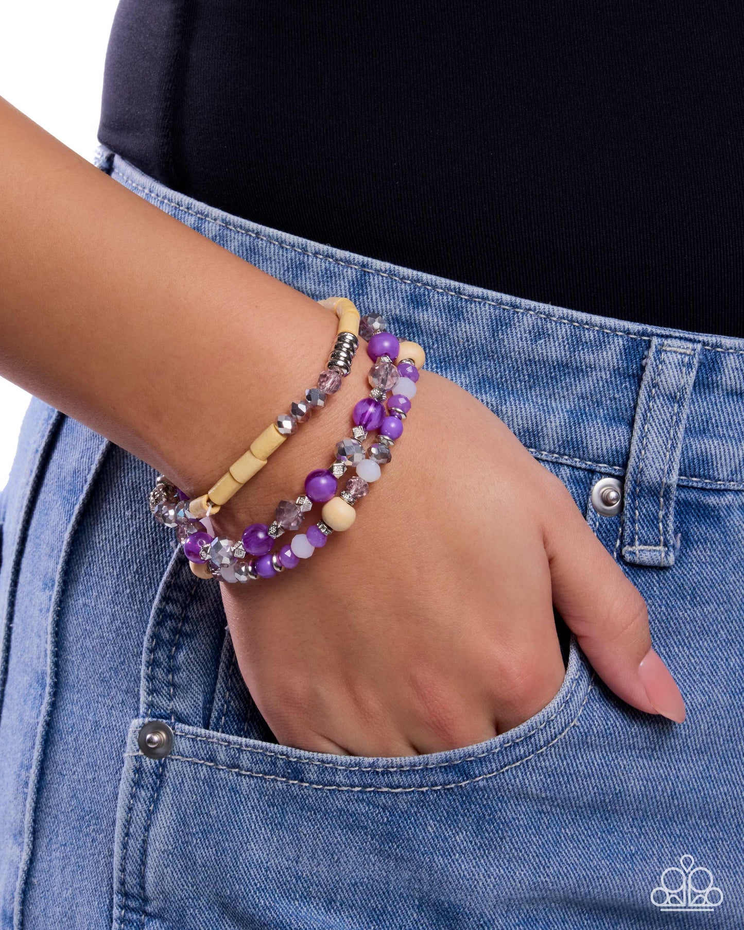 Hand wearing a beaded bracelet with denim background