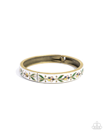 A gold-plated bangle bracelet with a white enamel background and a delicate floral pattern in green, yellow, and blue, shown on a plain white background.