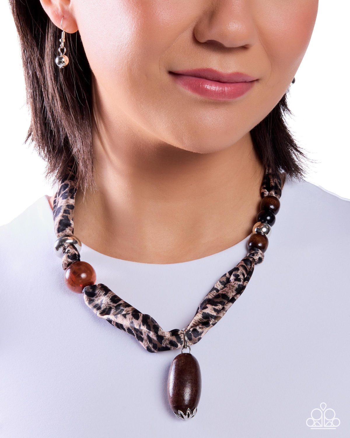 Necklace with leopard print pattern and large brown pendant worn by a person on a white background