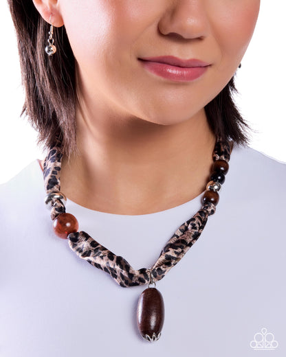 Necklace with leopard print pattern and large brown pendant worn by a person on a white background