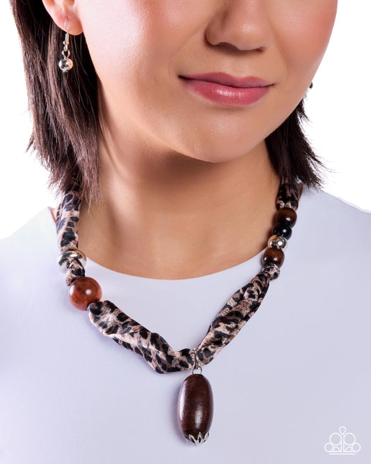 Necklace with leopard print pattern and large brown pendant worn by a person on a white background