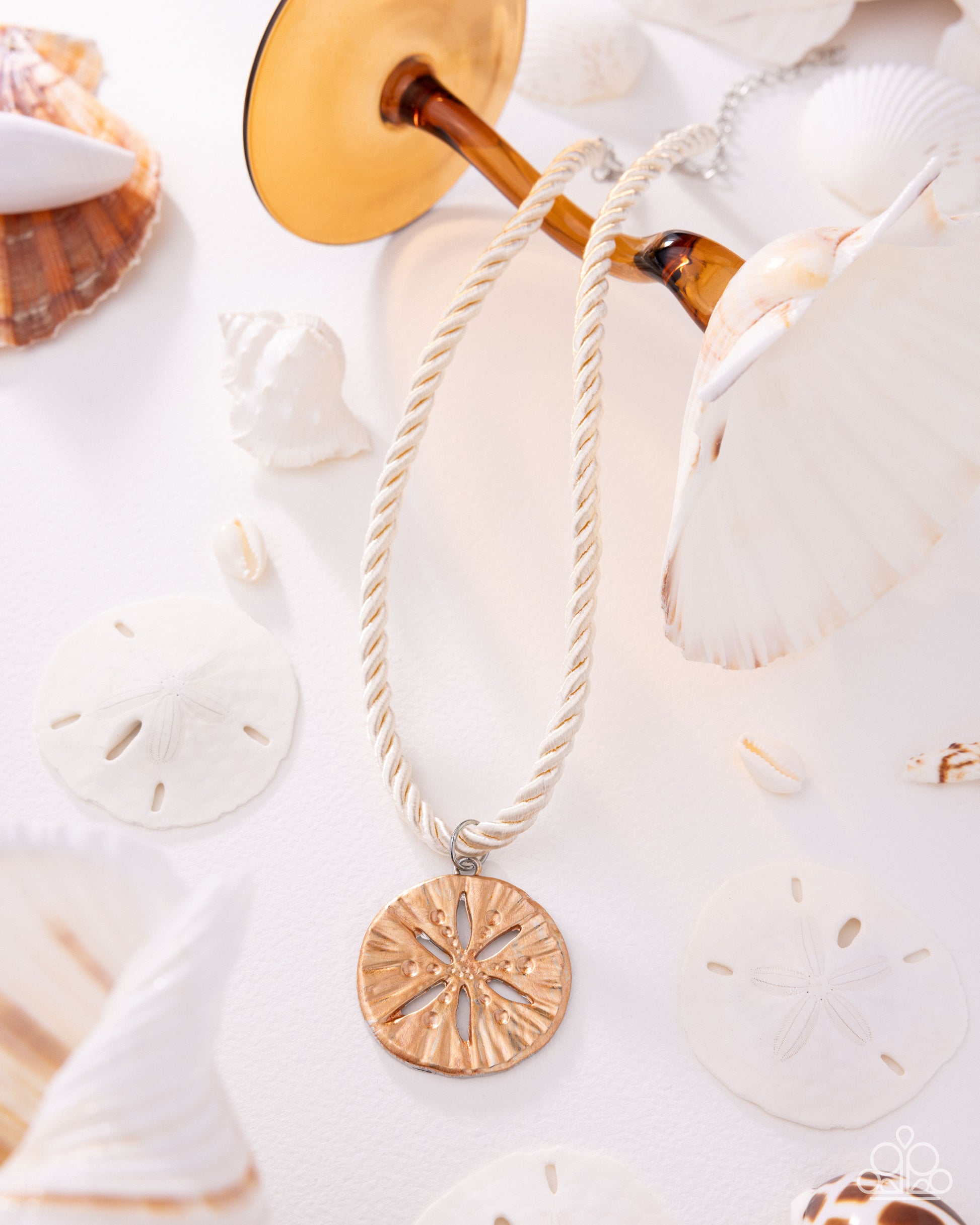 Necklace with a gold pendant on a white background with seashells