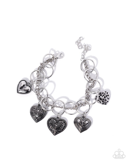 Silver charm bracelet with heart-shaped charms on a white background