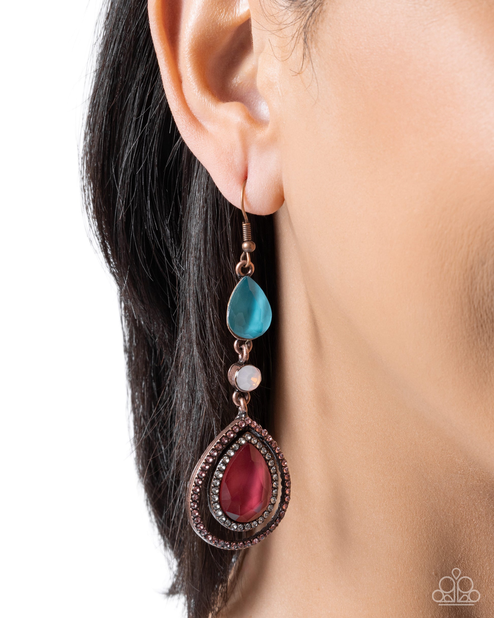 Close-up of an earring with a blue teardrop and red pendant on a white background