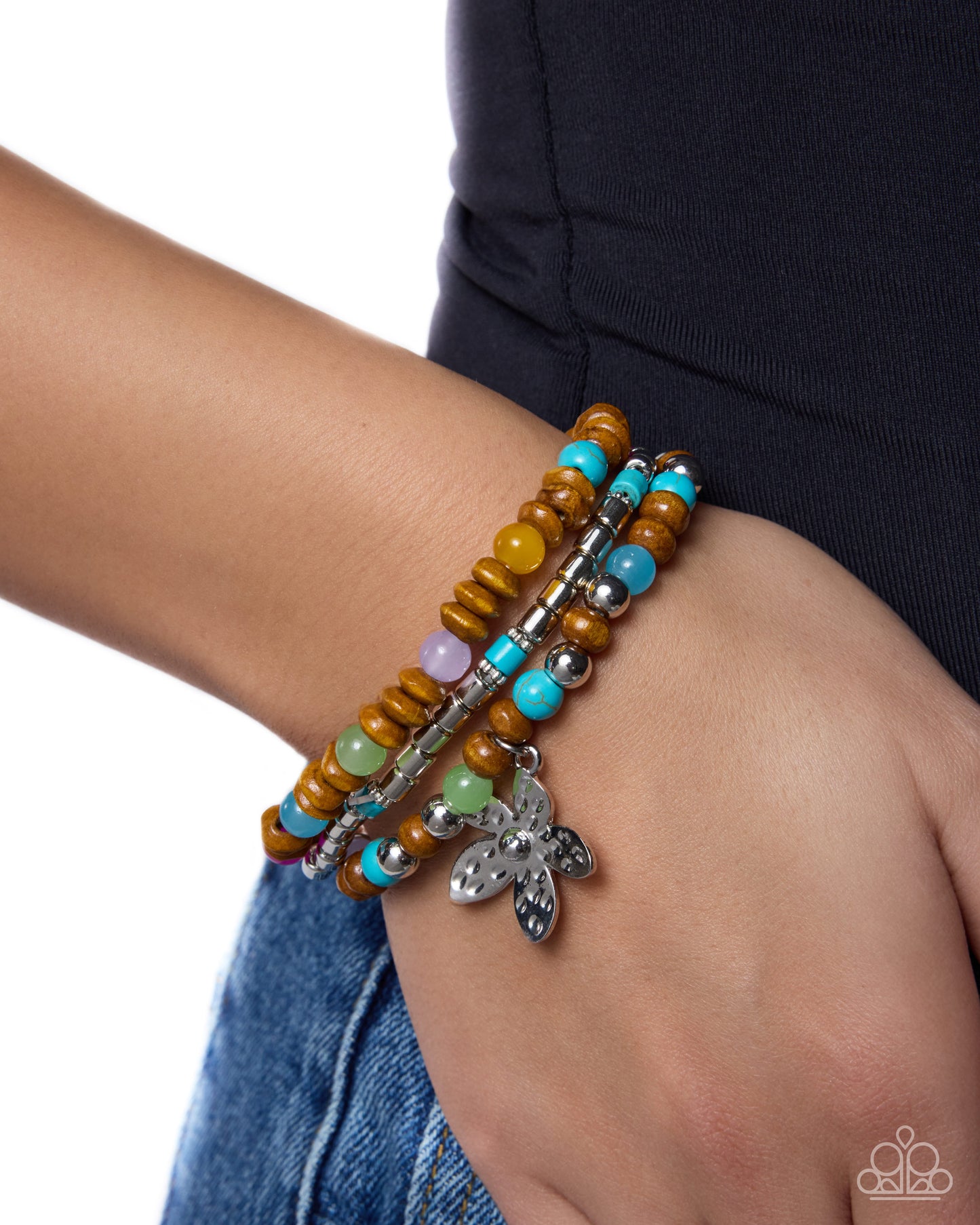 Multicolored beaded bracelet with silver charm on wrist against a white background