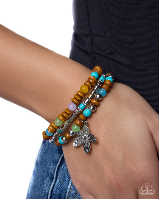 Multicolored beaded bracelet with silver charm on wrist against a white background
