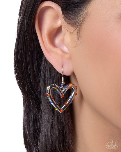 Heart-shaped earring worn by a person with dark hair on a white background