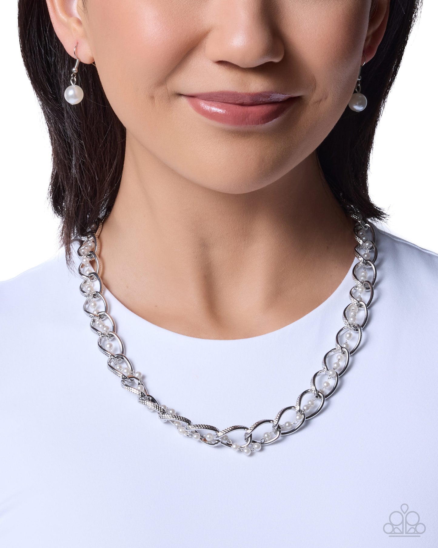 Close-up of a person wearing a silver chain necklace with white stones on a white background
