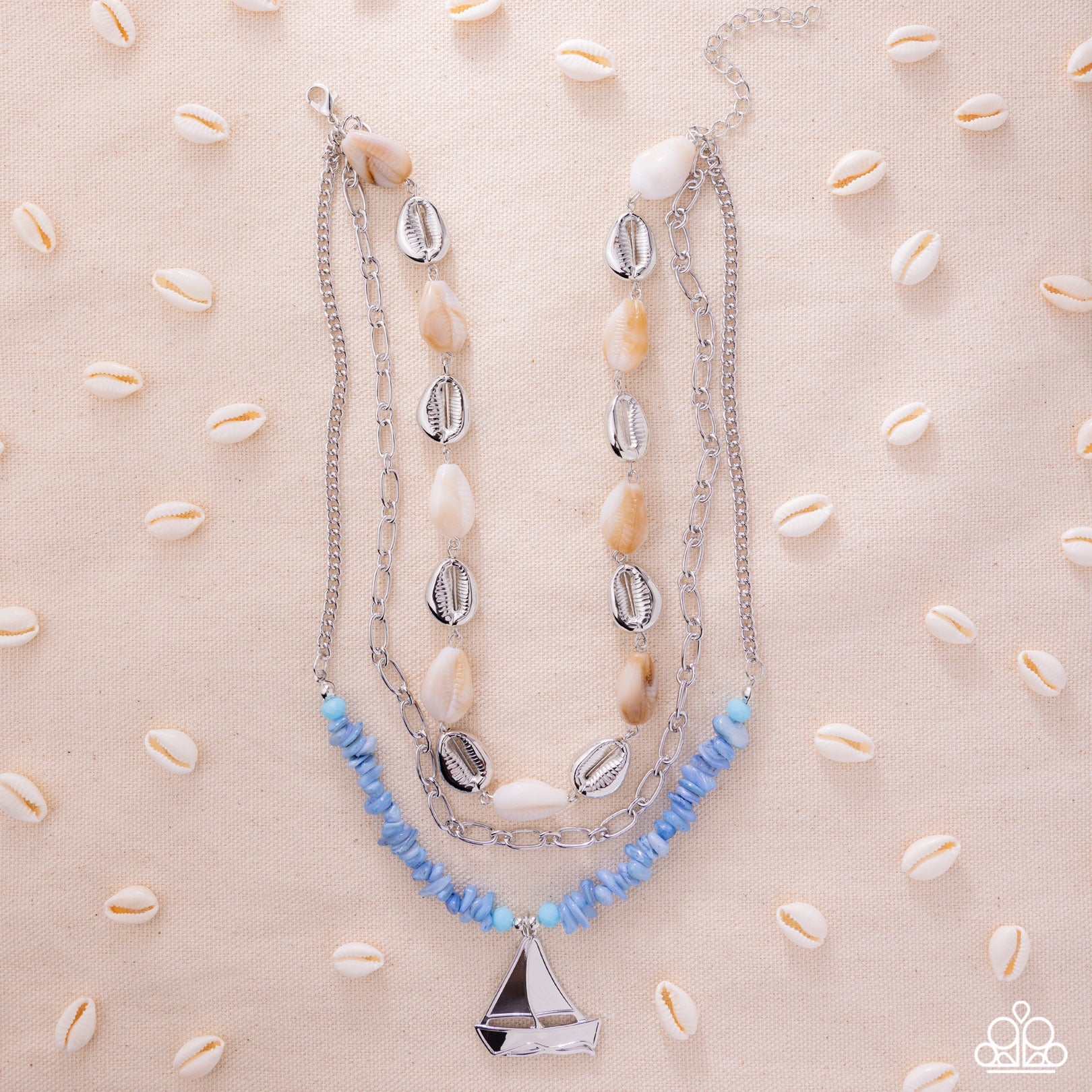 Necklace with shell and blue bead accents on a beige background with cowrie shells.