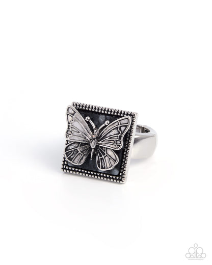 Silver butterfly ring with black square stone on a white background