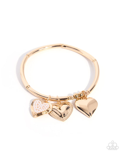 A gold-plated bangle bracelet with three dangling heart charms, including one textured heart and one with a small pavé center, on a white background.