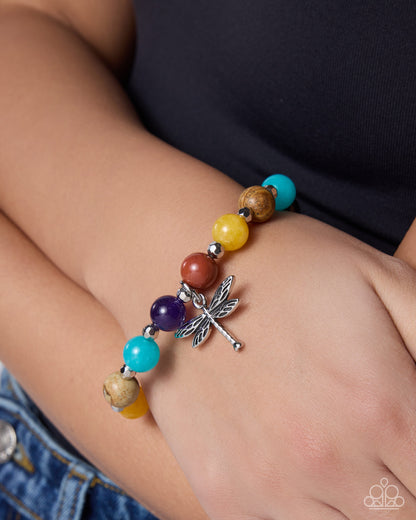 Colorful beaded bracelet with a dragonfly charm on a wrist.