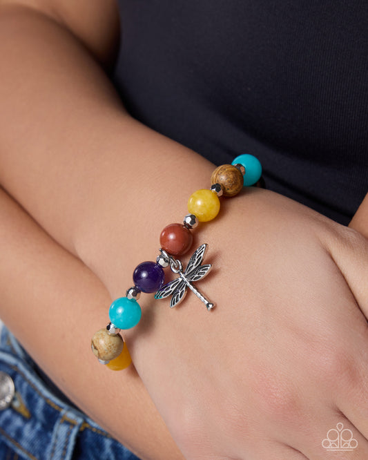 Colorful beaded bracelet with a dragonfly charm on a wrist.