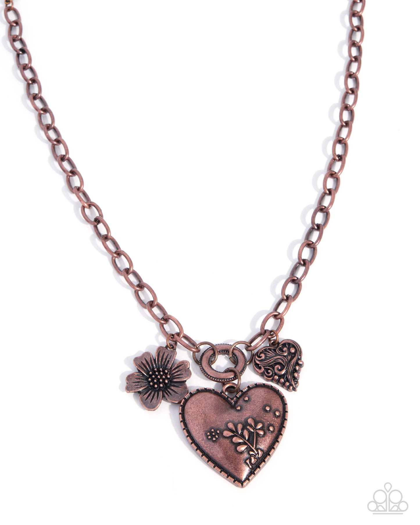 A copper-toned pendant necklace featuring a main heart-shaped locket with floral engravings, a smaller heart charm, and a flower charm, displayed on a clean white background.