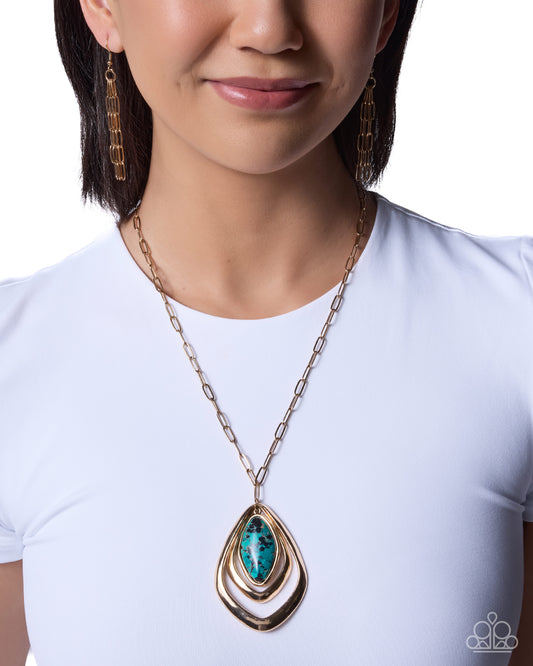 A close-up of a model wearing a gold chain necklace with a teardrop-shaped pendant featuring a turquoise-colored stone and gold concentric bands, paired with matching gold drop earrings.