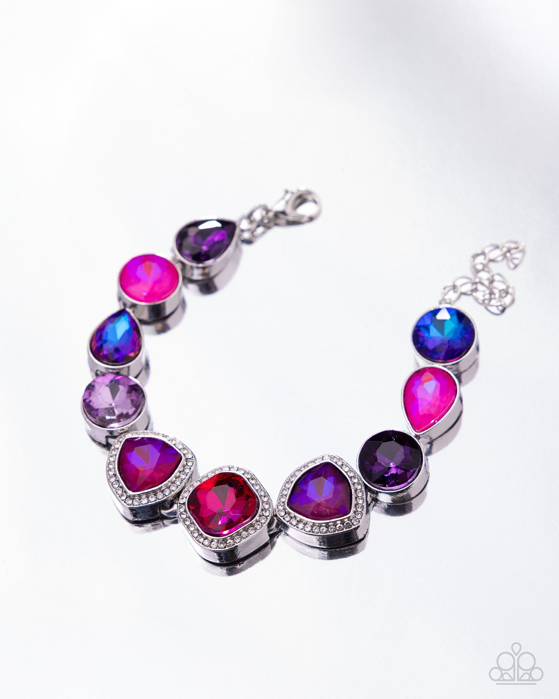 A silver-tone bracelet featuring seven faceted gemstones in vibrant shades of magenta, purple, and blue, accented with small clear crystals, shown on a white background.