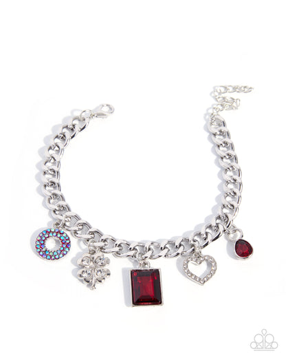A silver-tone charm bracelet featuring a curb chain, a round rhinestone donut charm, a silver floral charm, a rectangular red gemstone charm, a heart-shaped crystal charm, and a small red gemstone charm, displayed on a clean white background.