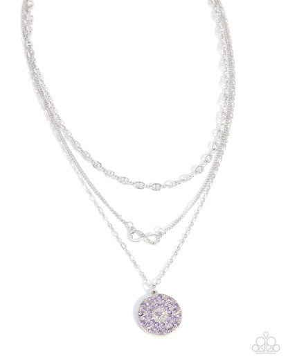 A silver-toned double-strand necklace featuring a round pendant adorned with light purple crystals, set against a plain white background.