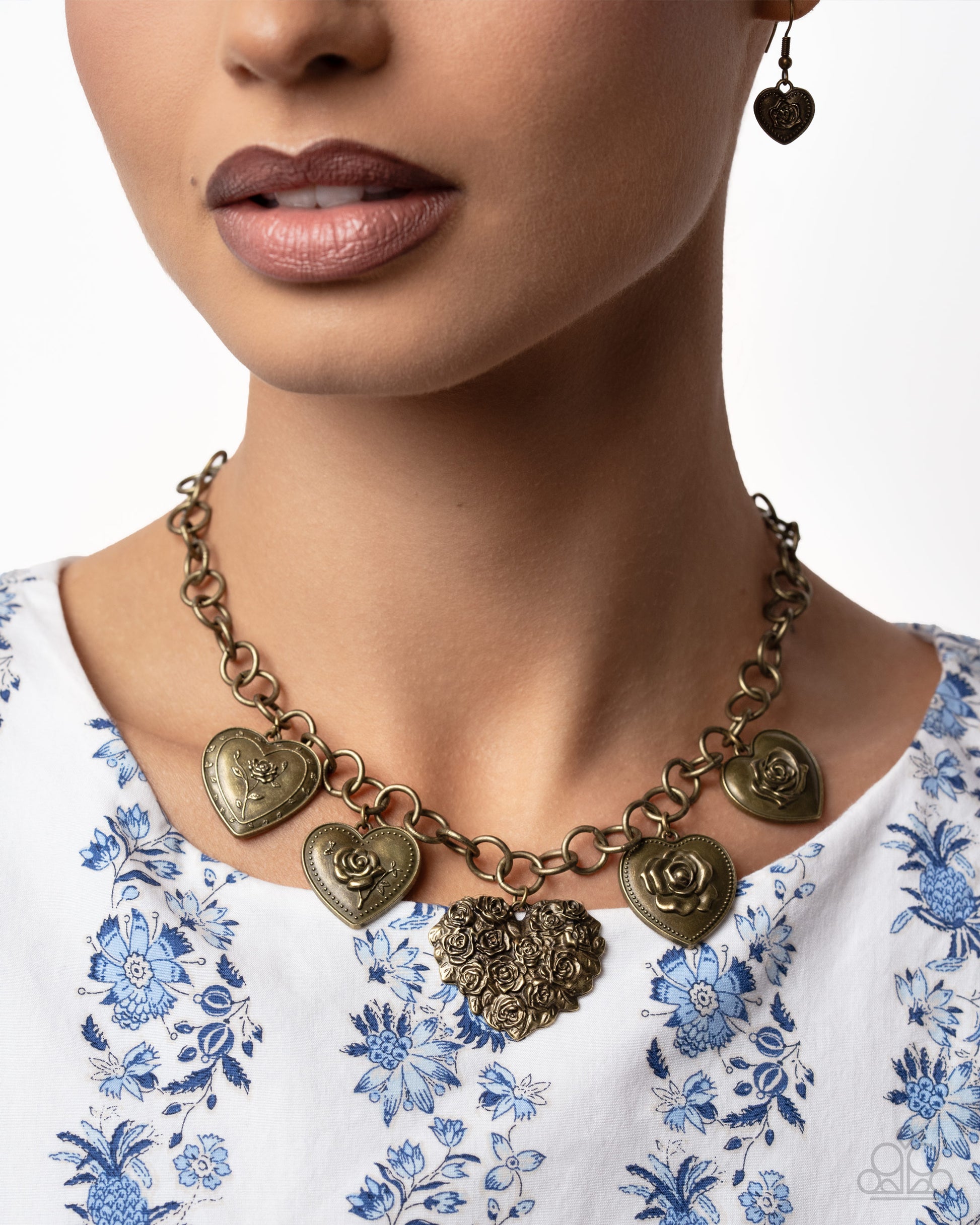 Close-up of a woman wearing a decorative necklace with heart-shaped pendants on a white background.