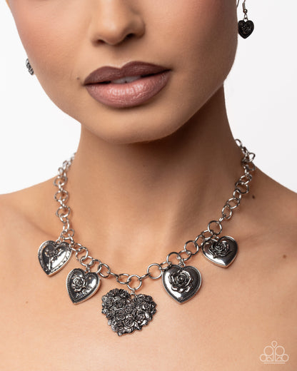 Necklace with heart-shaped pendants worn by a model on a plain background