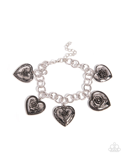 Silver bracelet with heart and rose-shaped charms on a white background