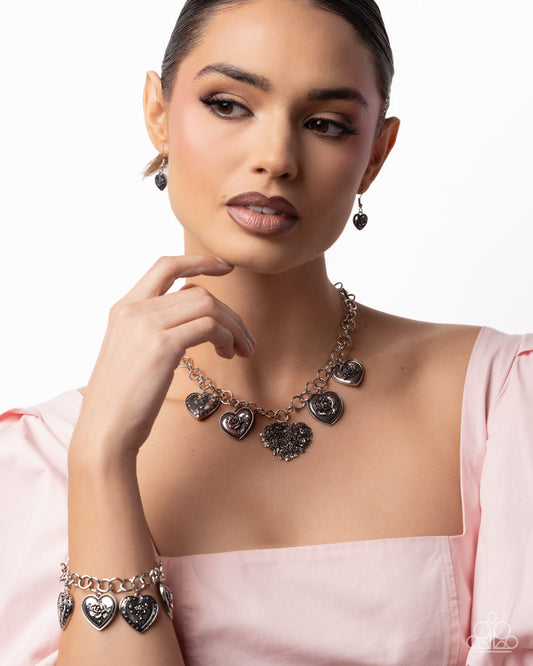 Woman wearing a necklace with heart-shaped pendants on a plain background