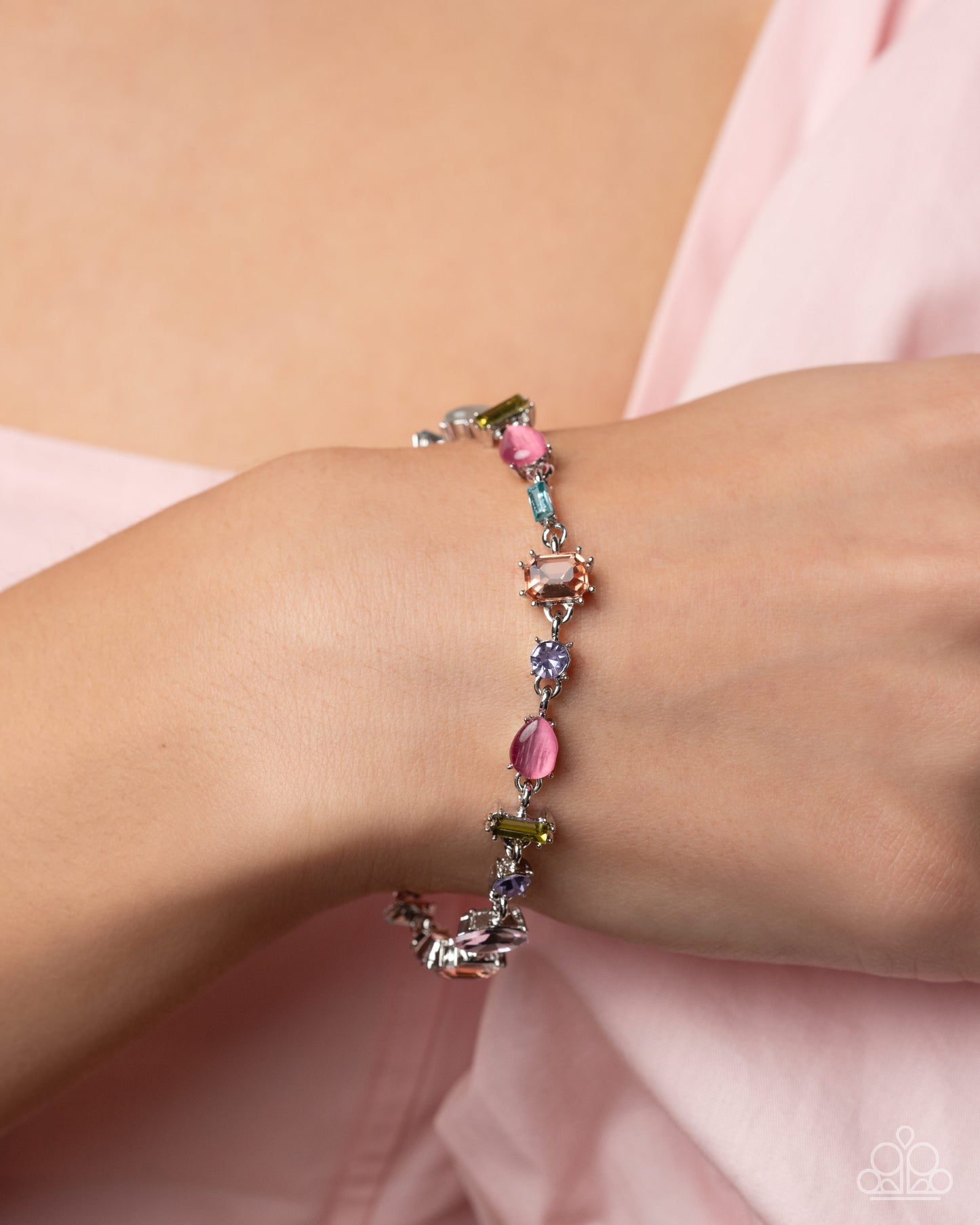 Multicolored beaded bracelet on a wrist with a soft pink background