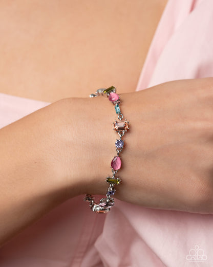 Multicolored beaded bracelet on a wrist with a soft pink background