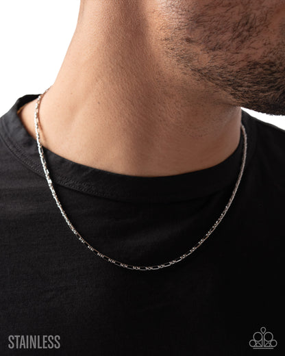 Silver chain necklace worn by a person on a black background with 'Stainless' text.
