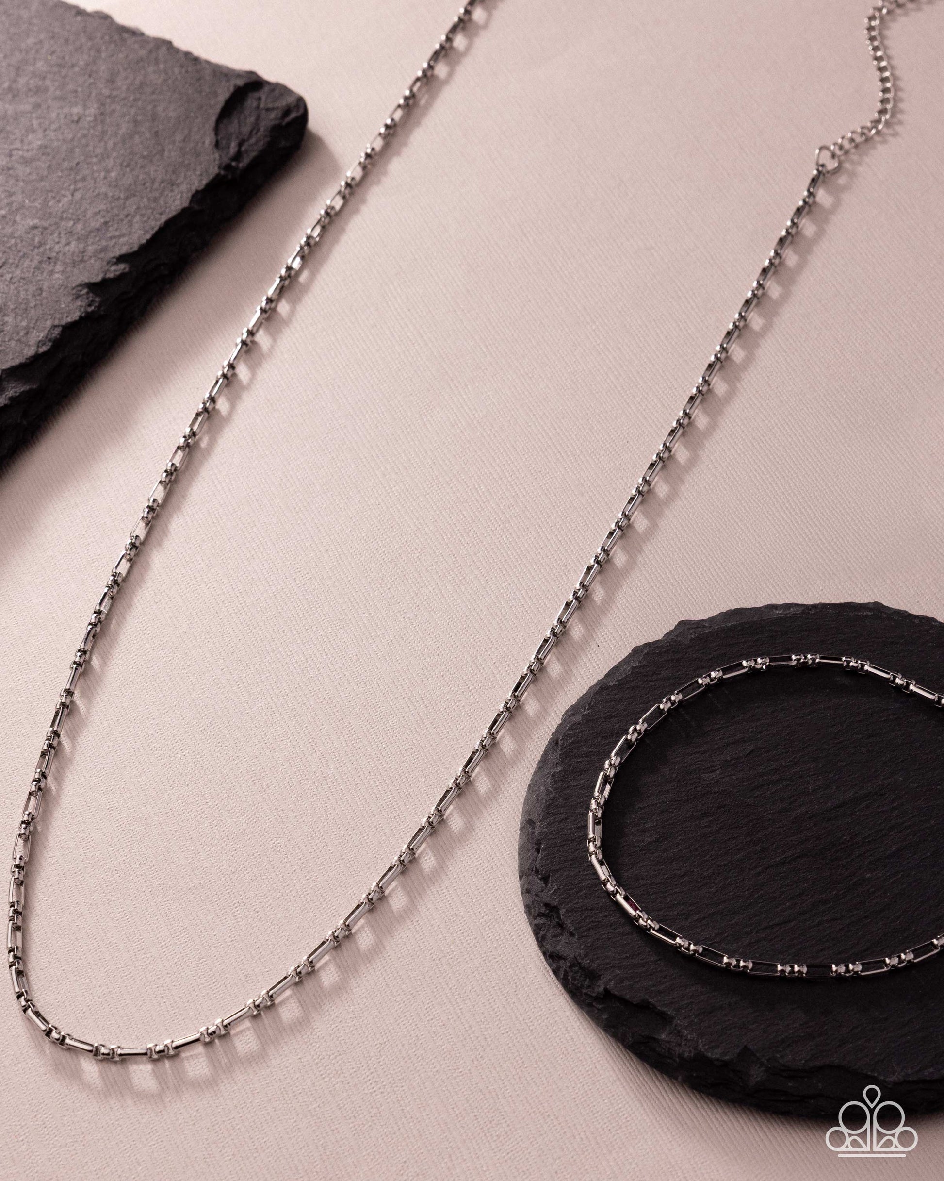 Silver chain necklace on a light surface with black stones